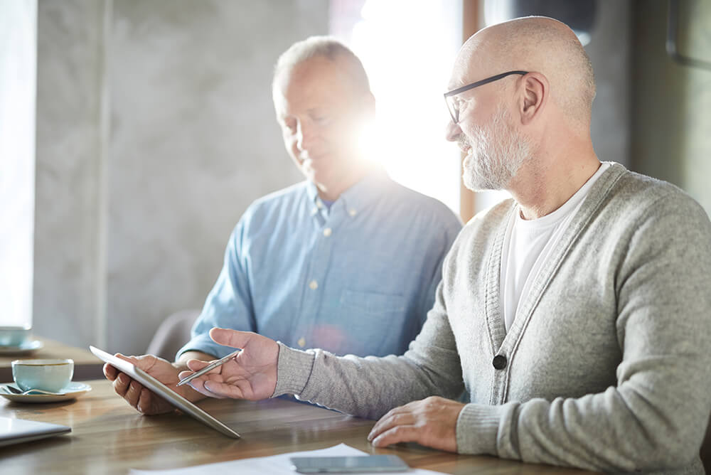 colleagues sitting at table and using tablet